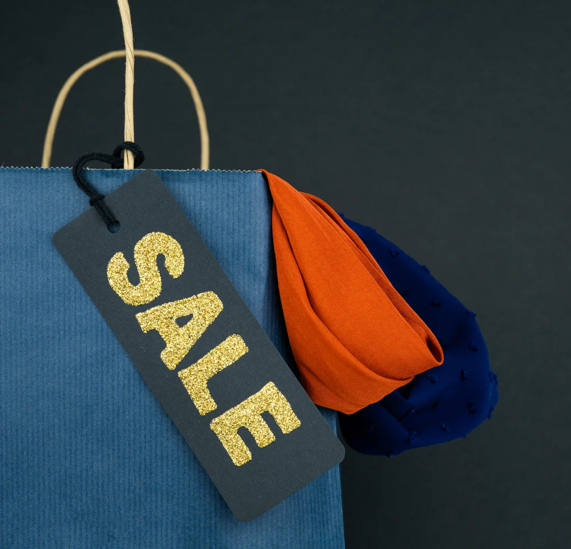 blue paper bag with black label with sale text dark background copy space vertical photo